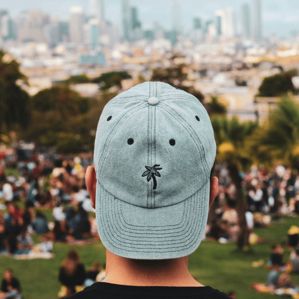A person wearing a baseball cap from behind, looking out over a city.